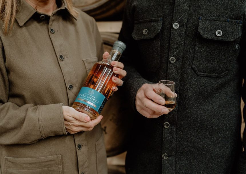 Male and female wearing McNair shirts holding a bottle of Wire Works Alter Ego Whisky